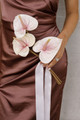 Bridesmaid holding the Blush Anthurium Petite Bouquet featuring three blush pink anthuriums with flowing ivory ribbon against a brown satin dress.