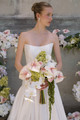 Bride holding a cascading bouquet with blush anthuriums, orchids, hydrangeas, and trailing amaranthus.