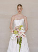 Bride holding a cascading bouquet with blush anthuriums, orchids, hydrangeas, and trailing amaranthus.