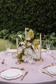Floral arrangement featuring white hydrangeas, blush anthuriums, white orchids, pale pink roses, calla lilies, and soft blush garden roses, styled in the middle of a wedding reception table with gold candlesticks.