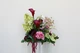Floral centerpiece featuring deep burgundy and white anthurium, green cymbidium orchids, pale green hydrangea, blush pink peonies, airy pink peonies, and cascading burgundy amaranthus.