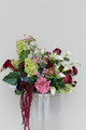 Floral Meadow featuring deep burgundy calla lilies, white calla lilies, blush peonies, pale green hydrangeas, green cymbidium orchids, burgundy roses, white anthuriums, cascading burgundy amaranthus, and airy pink accent blooms.