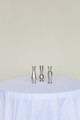 Three silver bud vases in different shapes on a white table in front of a white background.
