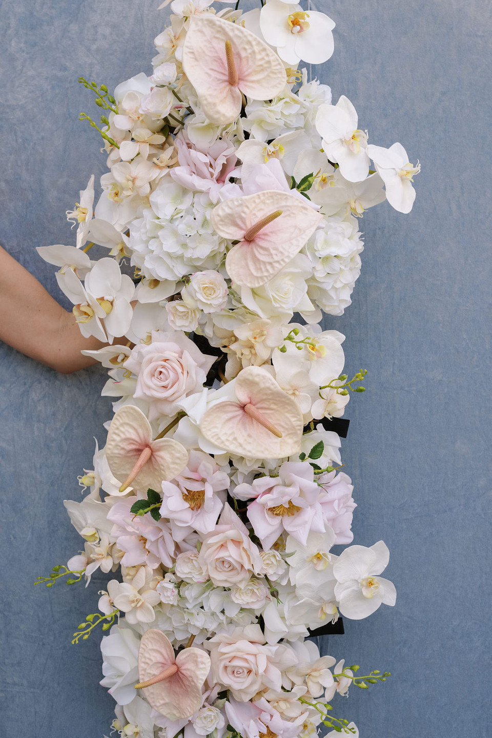 Floral arch arrangement with blush anthuriums, white orchids, hydrangeas, roses, and soft pink blooms.