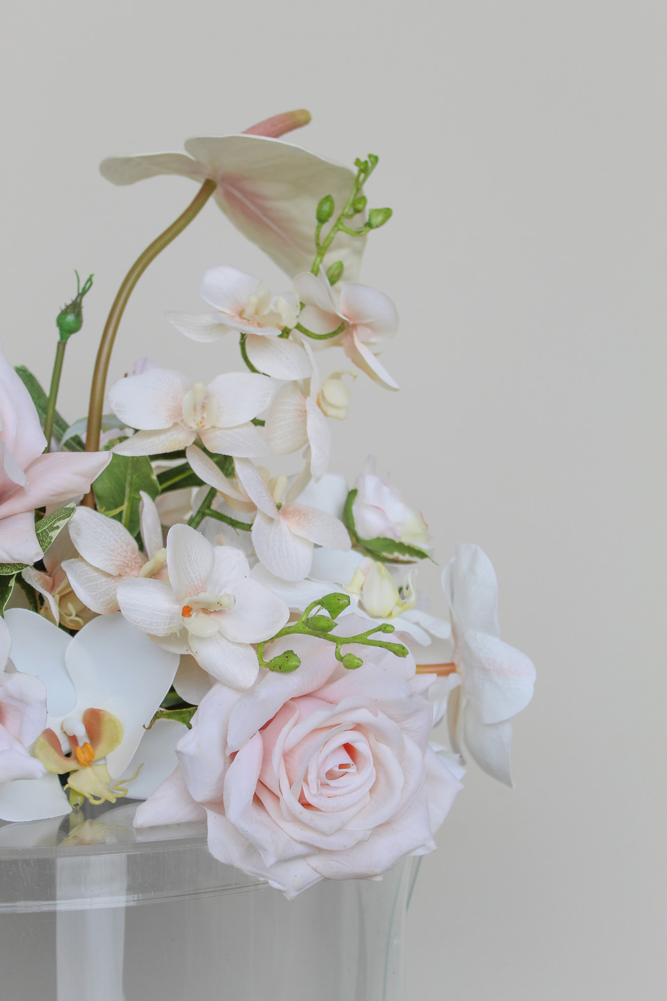 Close-up of a wedding floral arrangement featuring blush anthuriums, white orchids, pale pink roses, and soft blush blooms.