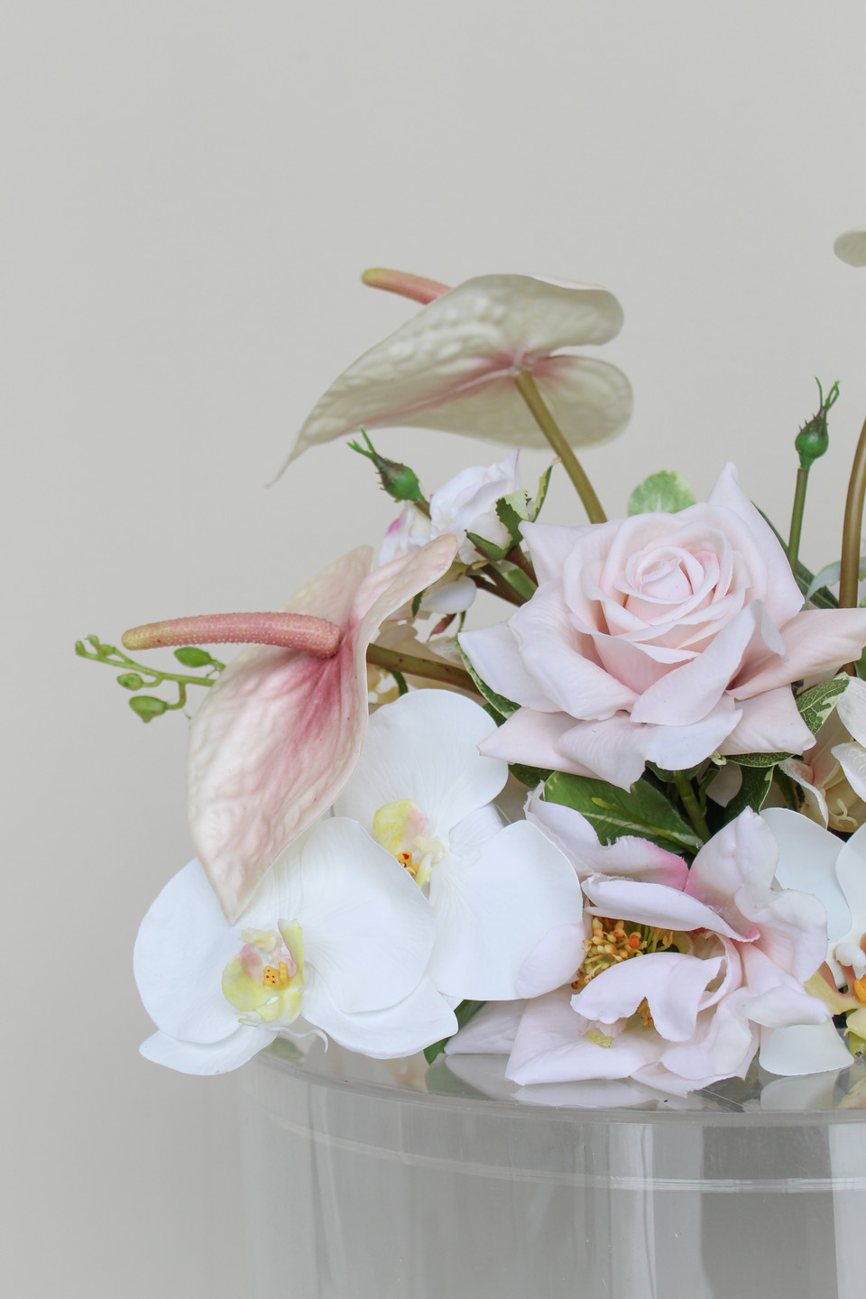 Close-up of a wedding floral arrangement featuring blush anthuriums, white orchids, pale pink roses, and soft blush blooms.