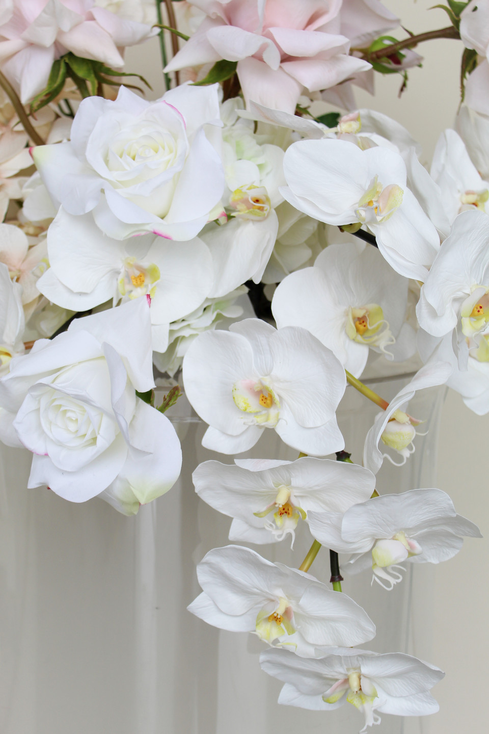 Close-up of cascading white orchids and ivory roses in a romantic wedding floral arrangement.