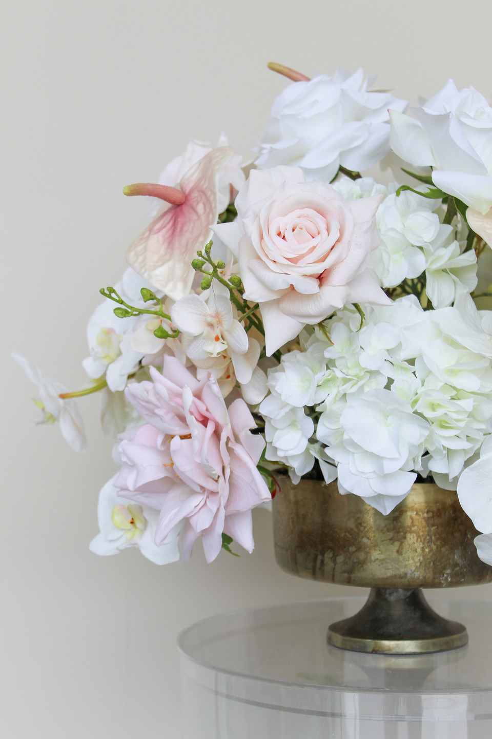 Grand centerpiece featuring white hydrangeas, white roses, blush roses, blush anthuriums, and cascading orchids in a gold compote vase.