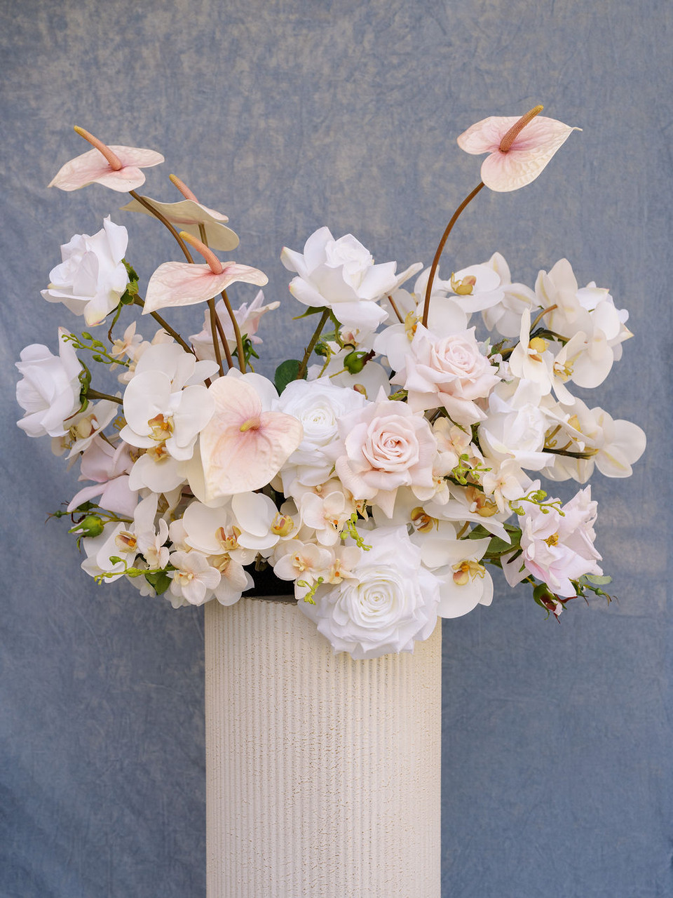 Garden-style floral arrangement featuring blush anthuriums, white phalaenopsis orchids, blush roses, and ivory blooms.