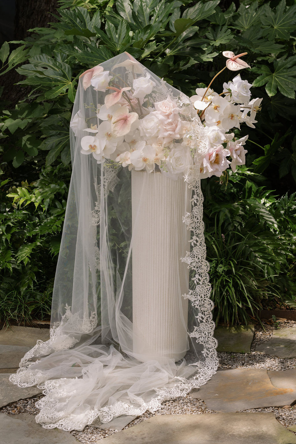 Wren Meadow floral arrangement styled with a lace bridal veil for a romantic wedding ceremony display.