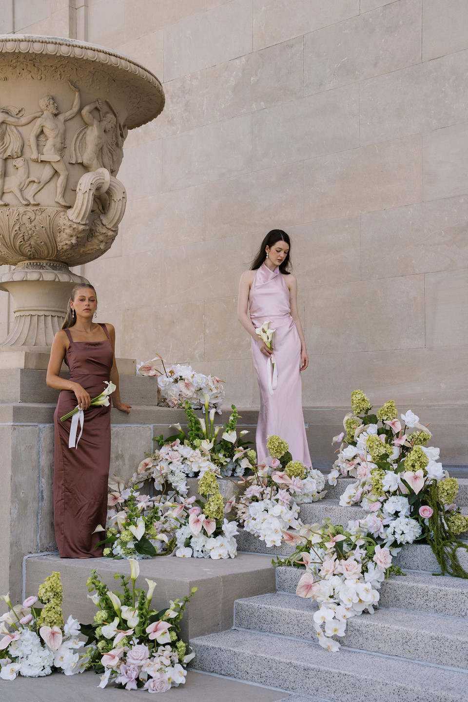 Bridesmaids standing on the steps with the steps covered in white, blush, and green florals.