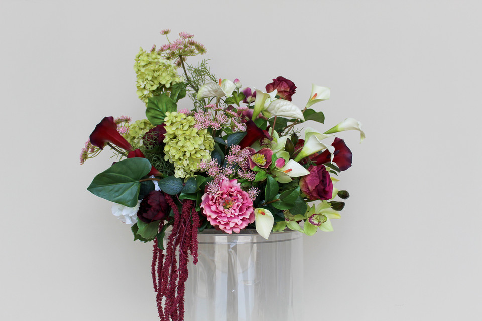Floral Meadow featuring deep burgundy calla lilies, white calla lilies, blush peonies, pale green hydrangeas, green cymbidium orchids, burgundy roses, white anthuriums, cascading burgundy amaranthus, and airy pink accent blooms.