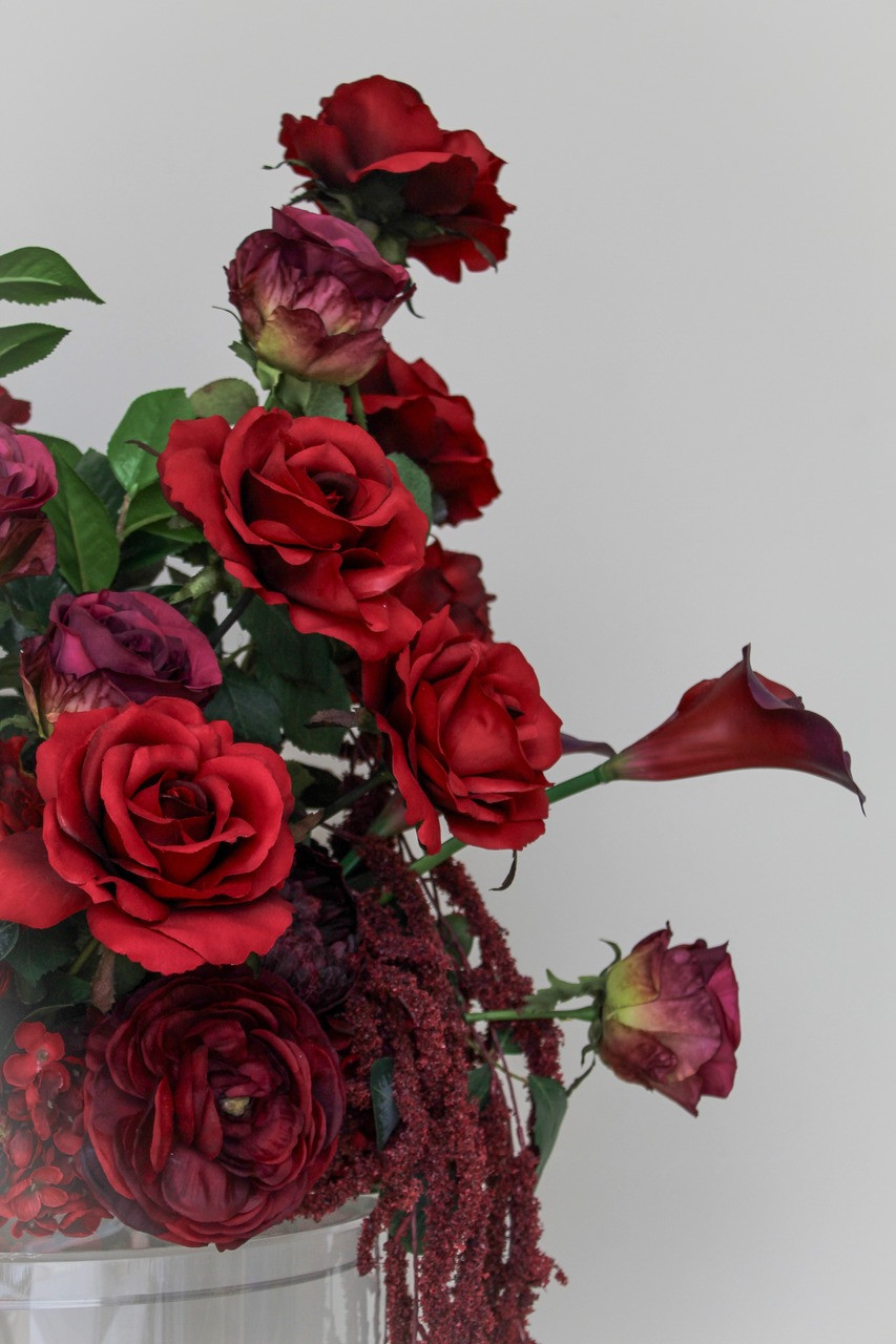 Stella Rouge Floral Meadow featuring rich red roses, deep burgundy peonies, burgundy calla lilies, garden roses, cascading burgundy amaranthus, and lush greenery. This premium silk floral arrangement creates a bold, dramatic statement for wedding aisles, sweetheart tables, ceremony backdrops, and reception décor.