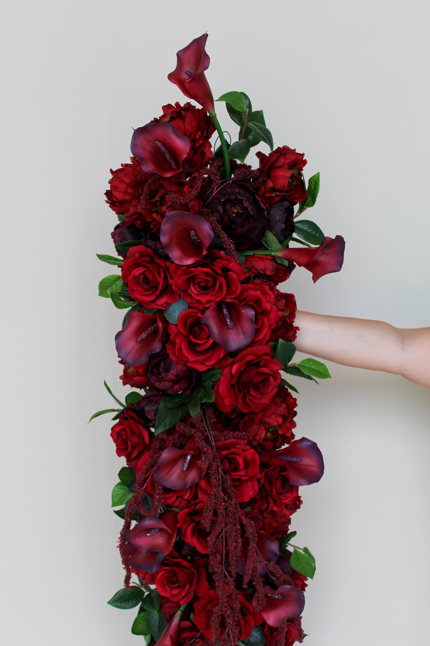 Luxurious burgundy floral runner featuring rich red roses, deep burgundy peonies, burgundy calla lilies, cascading burgundy amaranthus, and lush greenery. This premium silk floral table runner creates a dramatic, romantic statement for wedding reception tables, sweetheart tables, and ceremony décor