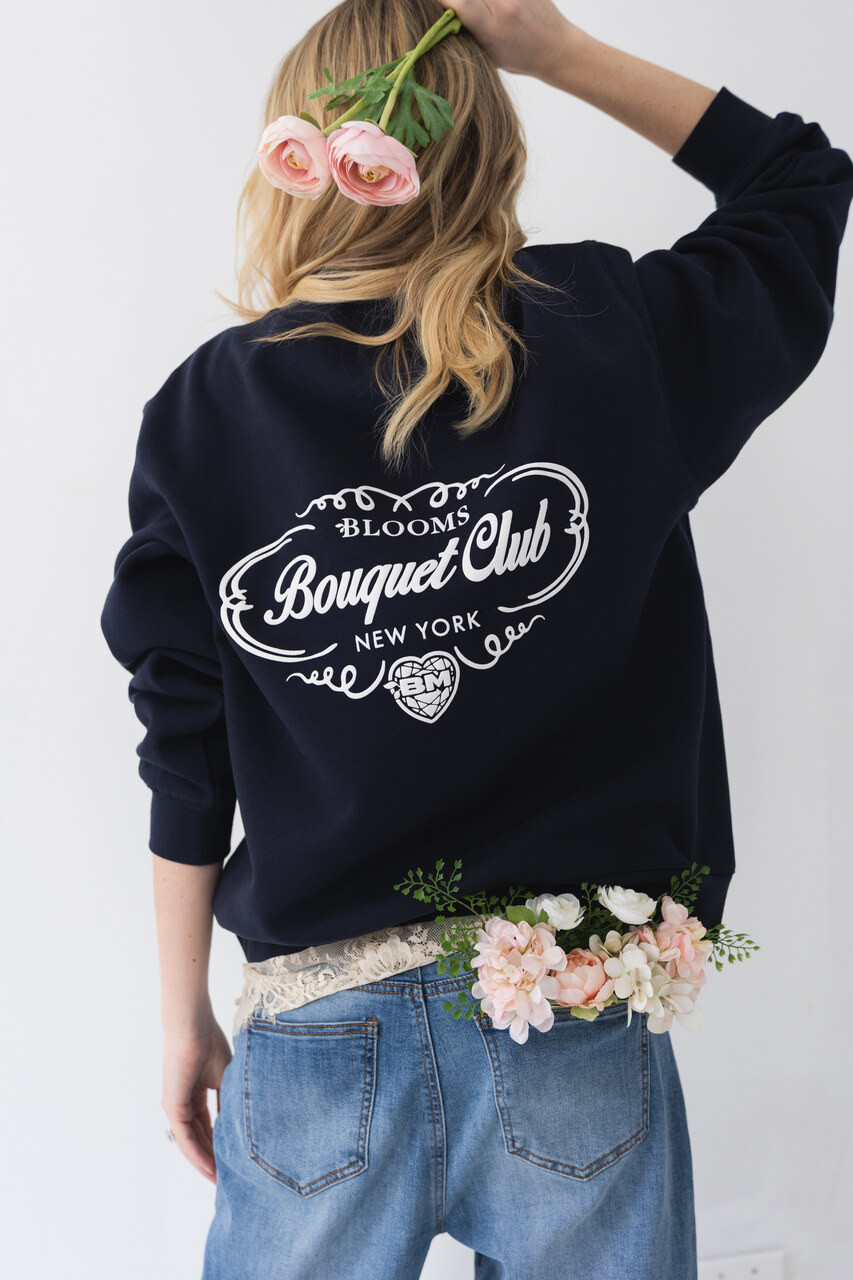 Woman wearing the back of a navy Bouquet Club mockneck sweatshirt with oversized Bouquet Club graphic.