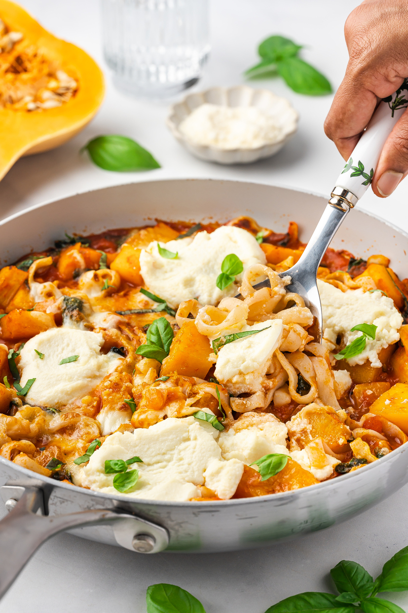 A person swirls a forkful of low carb pasta from a skillet filled with deconstructed butternut squash lasagna pasta.