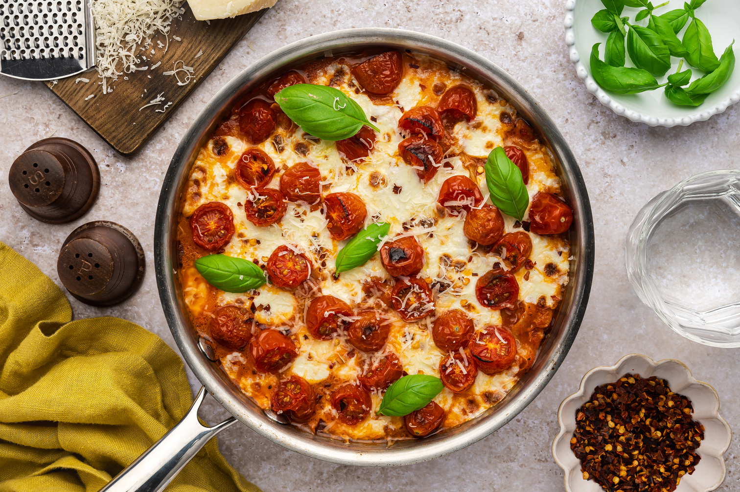A closeup, overhead image of a skillet of low-carb Margherita pasta made with It's Skinny fettuccine, cherry tomatoes, a spicy sauce, and tons of melted cheese.