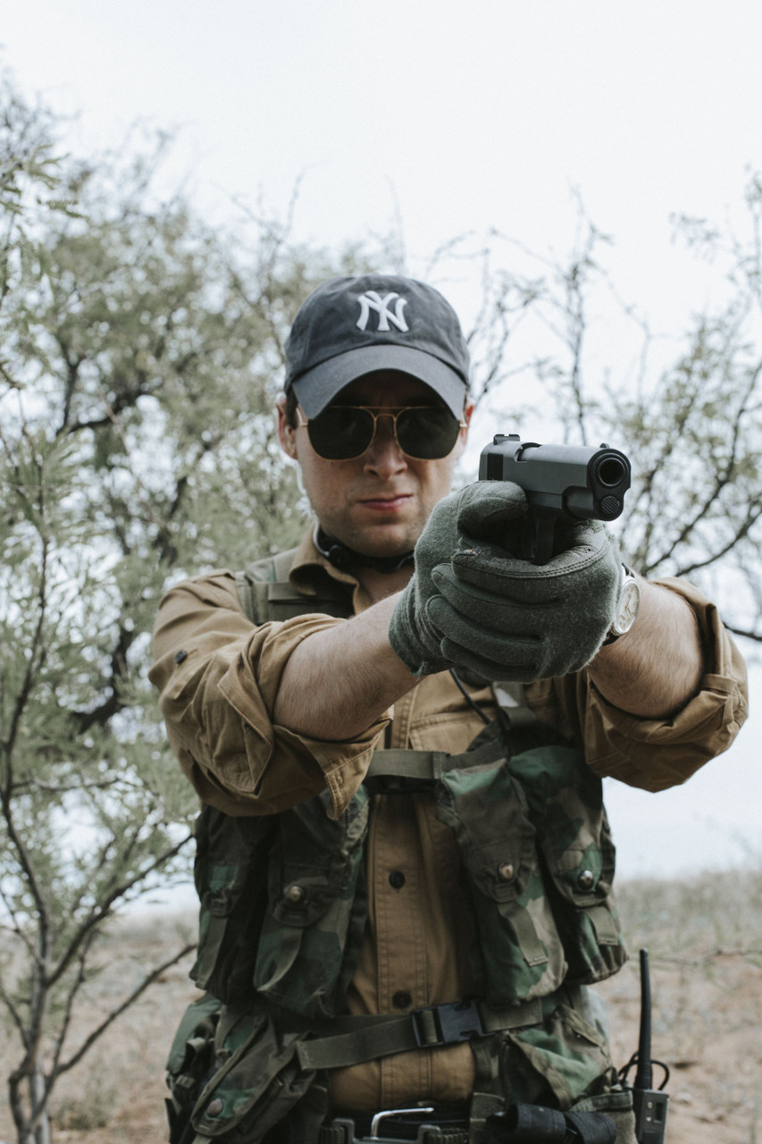 Lifestyle | 1911A1 Service | aimed at the camera, standing in the brush