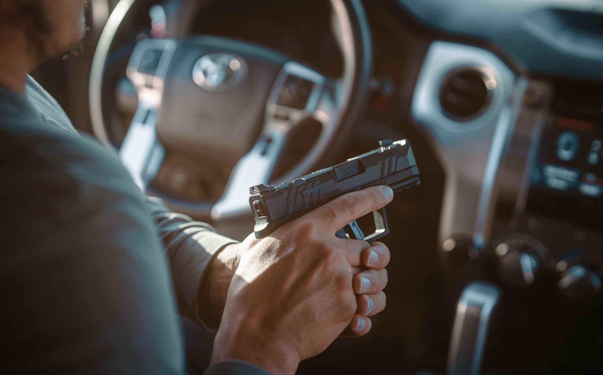 Tisas PX-9 pistol resting on the seat of a truck cab in low light