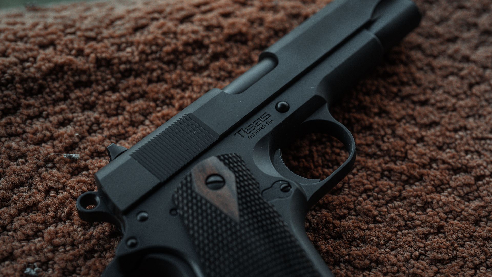 Dark steel Tisas 1911 with Buford GA engraving resting on wool
