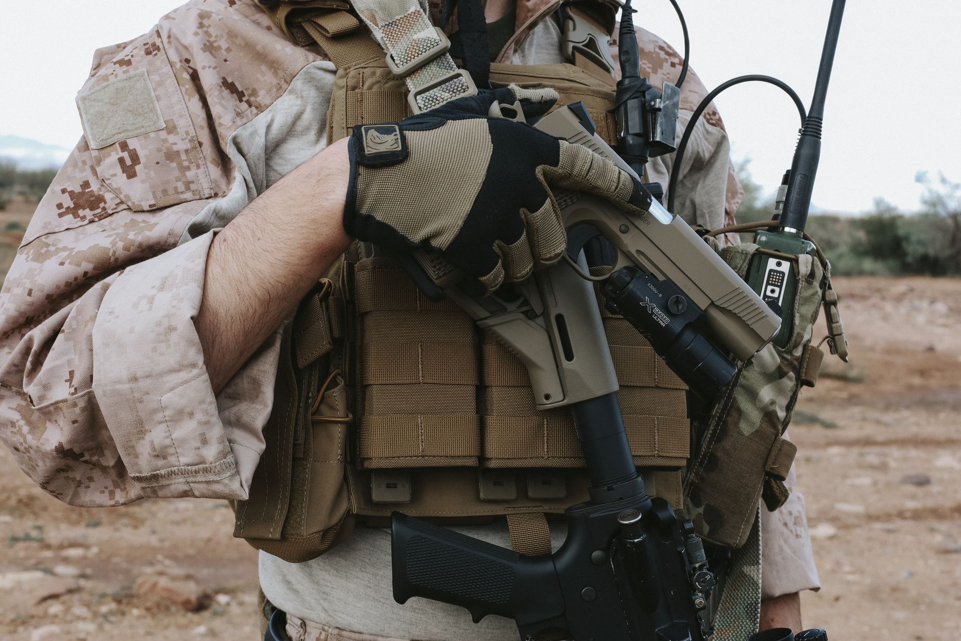 FDE Tisas Double Stack 1911 with weapon light drawn from a plate carrier in the desert