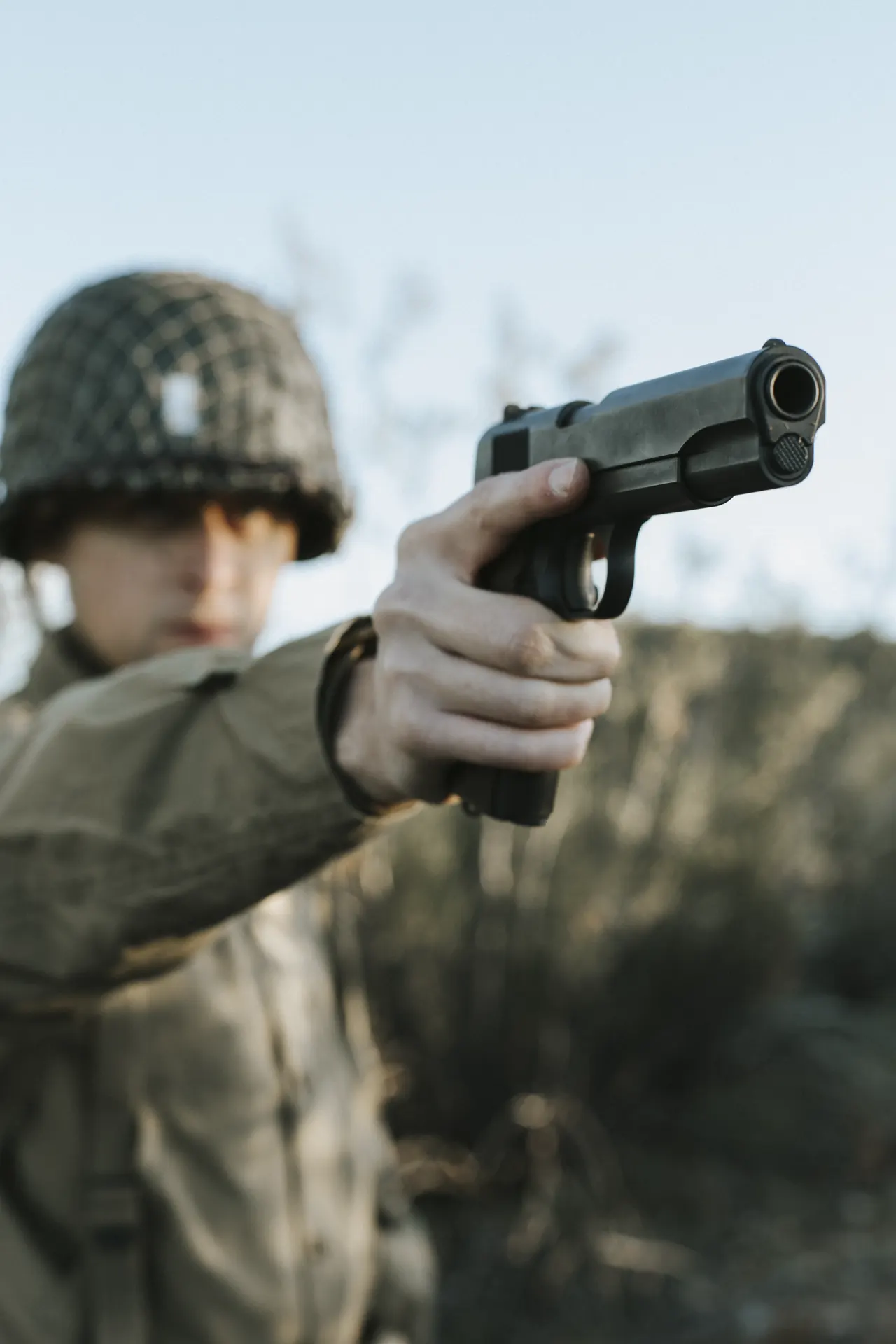 WWII pattern soldier aiming a 1911 against open sky