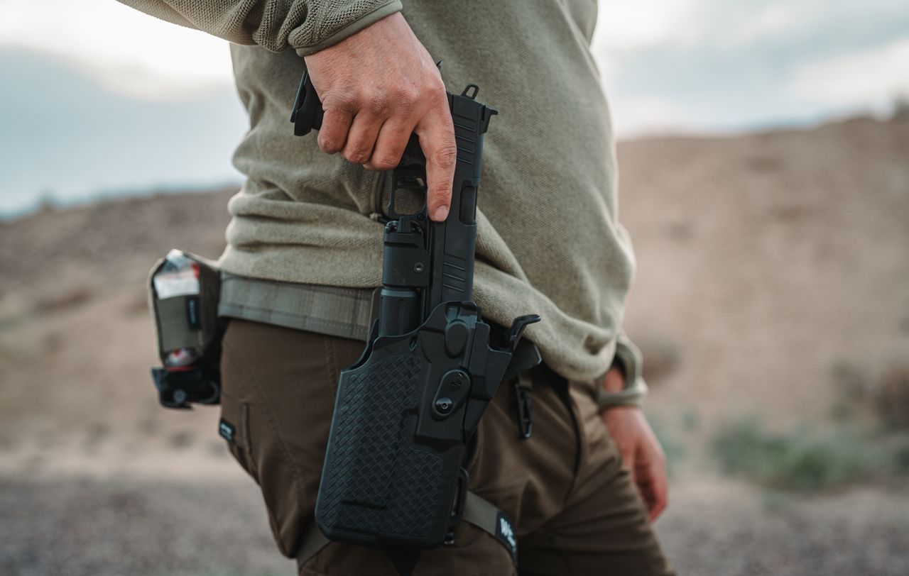 A compensated Tisas double-stack 9mm holstered with a weapon light