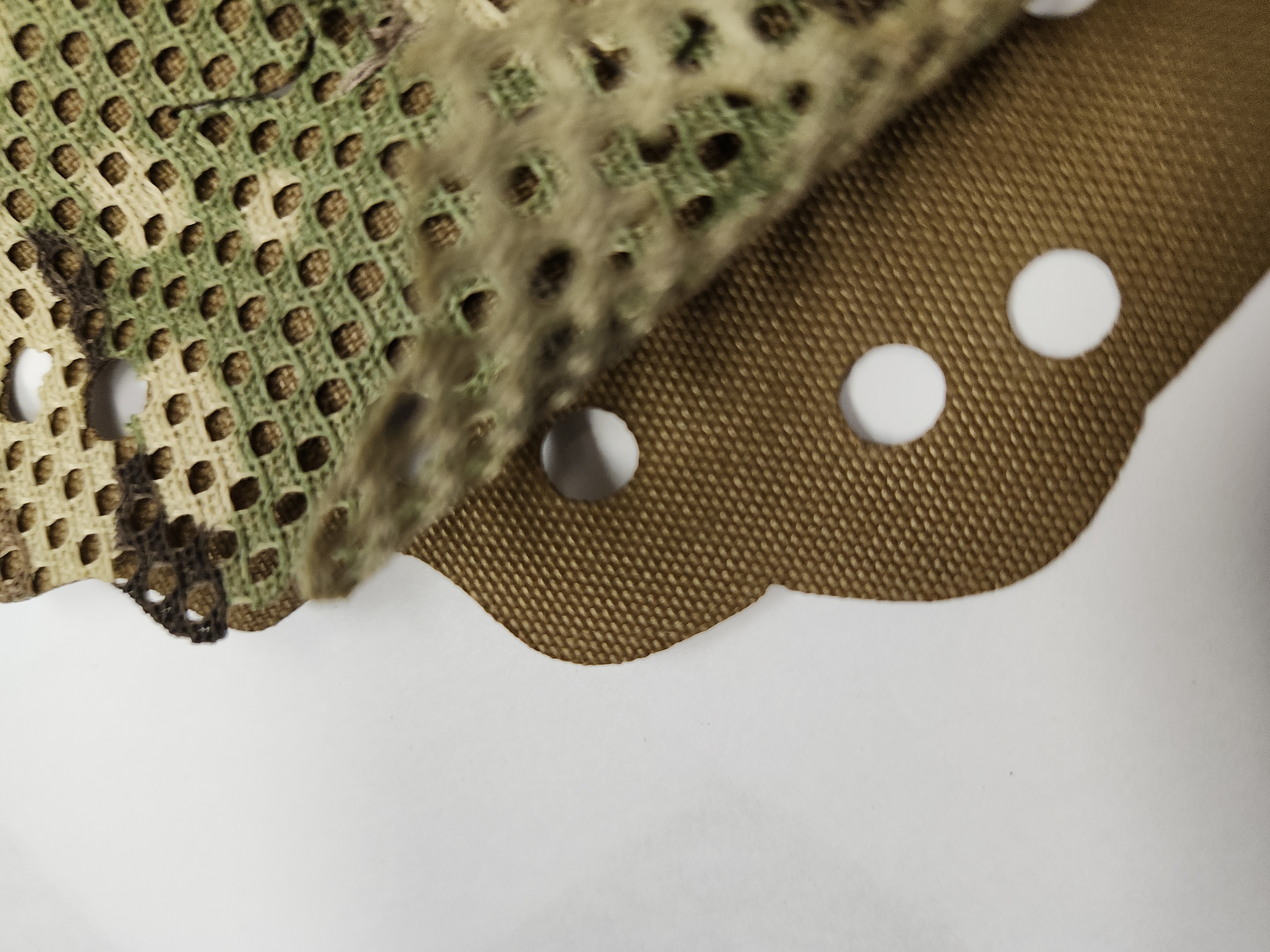 Close-up of Carcajou Tactical helmet scrim in Multicam showing laser-cut leaf pattern and dual-layer construction