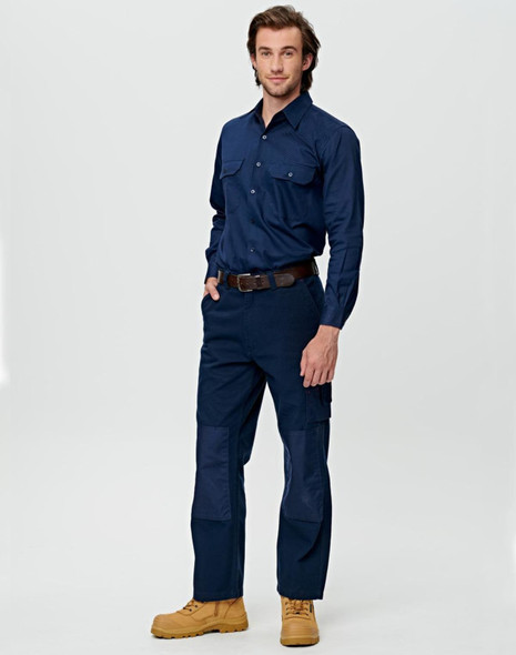 A man wearing beige work pants featuring pockets and reinforced knee patches, paired with a matching long-sleeve shirt.