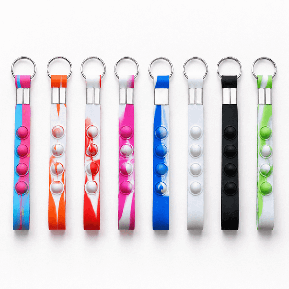 A selection of eight key chains in various colours, featuring popper buttons for stress relief. Each has a metal ring.
