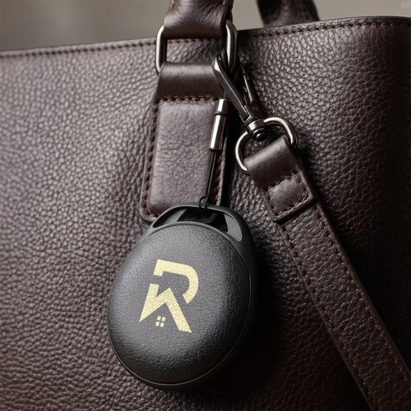 A black Bluetooth tracker attached to a brown leather bag, featuring a minimalist logo on its surface.