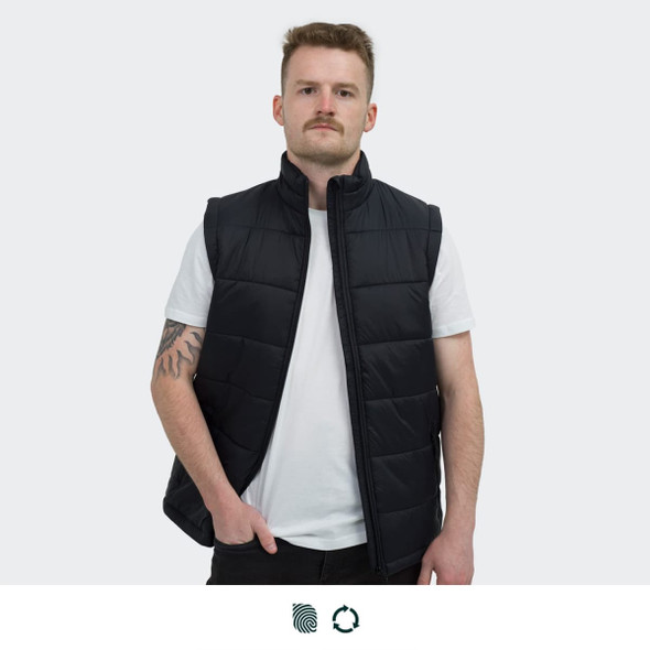 A man wearing a black puffer vest over a white t-shirt, standing against a plain background. The vest features a logo.