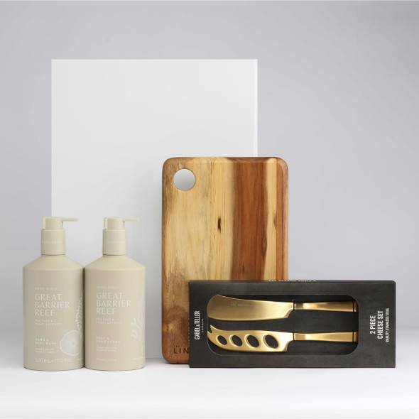 A wooden chopping board, two beige pump bottles, and a boxed set of gold-coloured utensils.