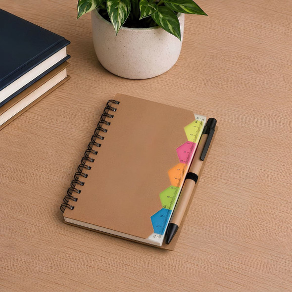 A brown spiral notebook sits on a wooden surface, accompanied by a pen and vibrant sticky notes in various colours.
