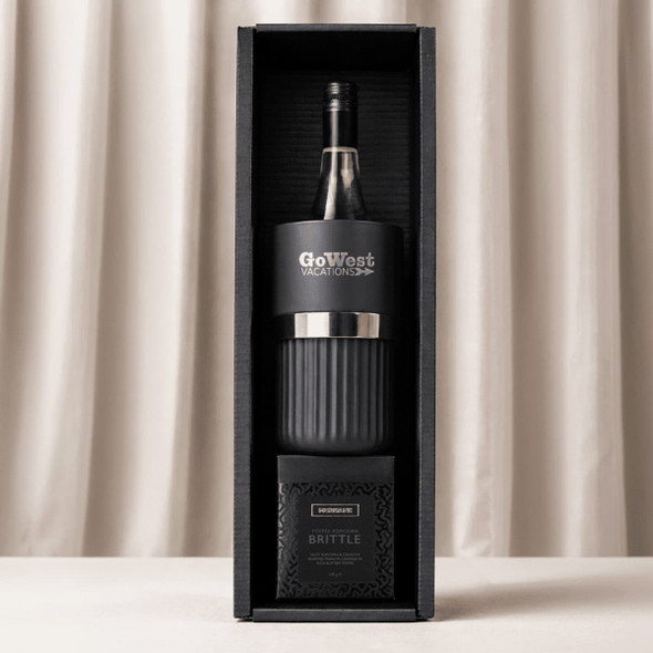 A black wine bottle cooler, a glass tumbler, and a box of brittle, all packaged in a stylish gift box.