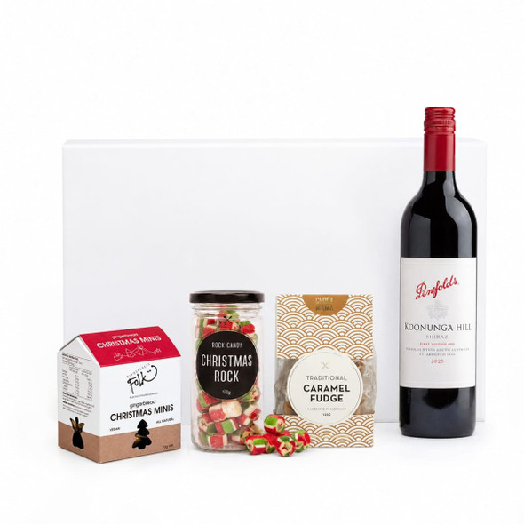 A drink bottle of red wine alongside Christmas-themed sweets: fudge, rock candy, and chocolate minis.