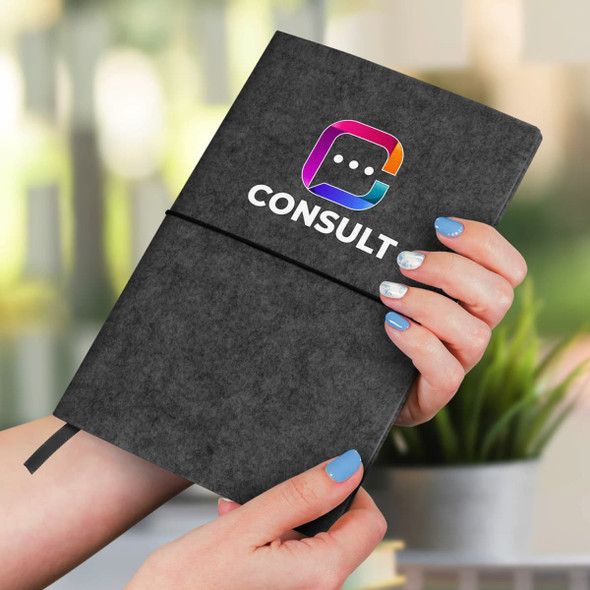 A person holds a grey RPET felt notebook with a logo, featuring a soft cover and elastic band closure.