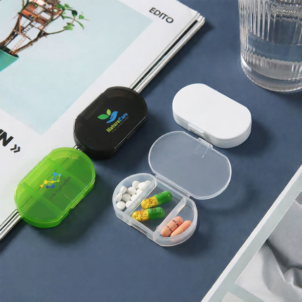 Three pill boxes in green, black, and white, displaying various pills inside a transparent compartment.