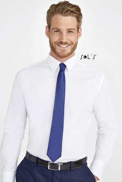 A man wearing a white shirt, dark blue tie, and dark trousers, with a logo visible on the shirt.