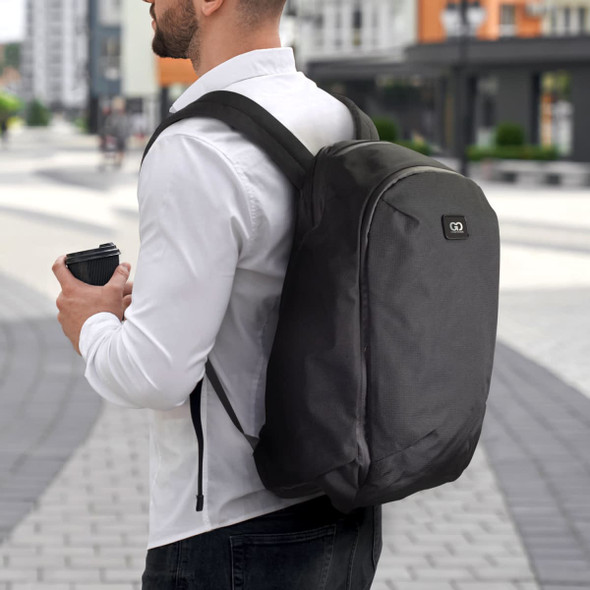 A black business computer backpack is worn on a person's back while they hold a coffee cup.