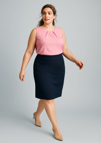 A woman walks in a pink sleeveless top and a navy blue lined pencil skirt, wearing beige heels.