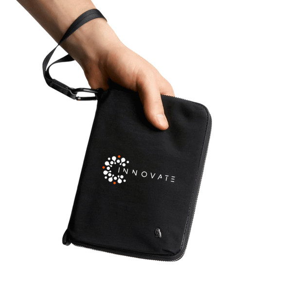 A black zipped toiletry bag with a wrist strap, featuring a logo on the front.