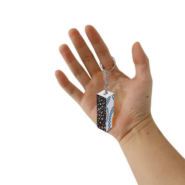 A custom square cube keyring held in a hand, featuring a multicolour design with geometric patterns.
