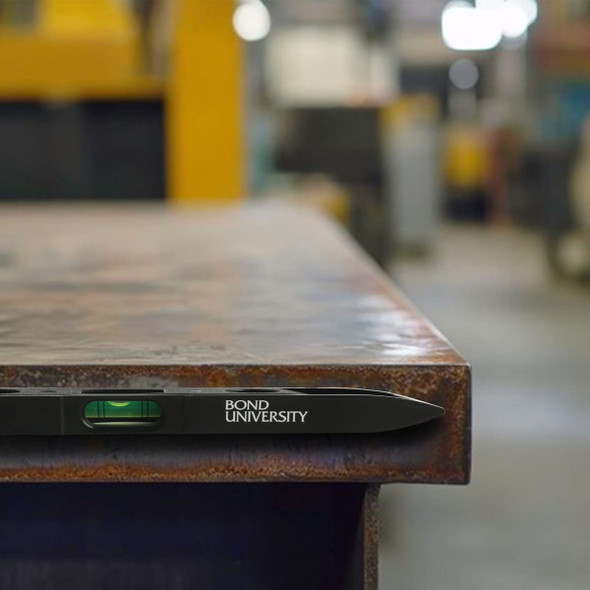 A magnetic torpedo level in black rests on a metal surface, featuring a liquid vial for measuring.