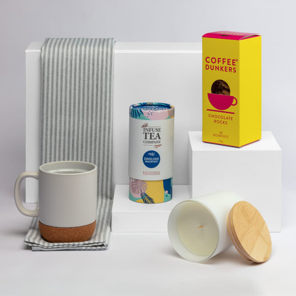 A drink bottle and cup set with a cork base, tea infuser, chocolate snacks, and a striped cloth napkin.