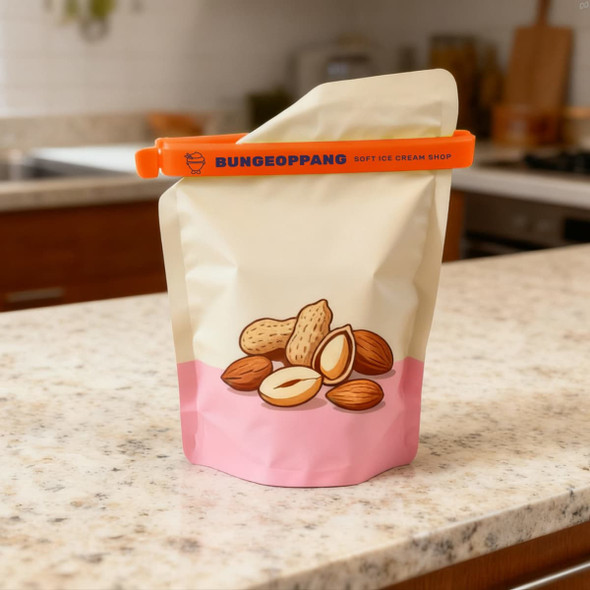 A large food bag seal clip in orange, securing a beige bag featuring illustrations of assorted nuts on a kitchen countertop.