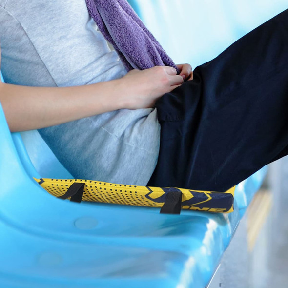 A foldable stadium cushion in yellow and black is resting on a blue seating area next to a person in casual attire.