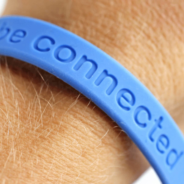 A blue silicone wristband featuring a debossed design, worn on a wrist.