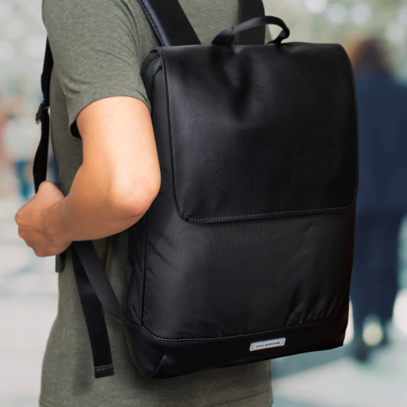 A black Moleskine Metro Slim Backpack is worn on a person's back, featuring a sleek design and a branding logo.