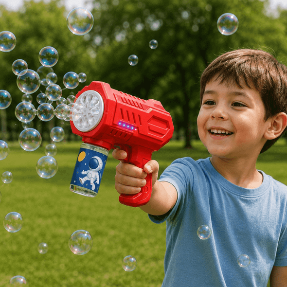 A red bubble gun with a blue canister, producing numerous bubbles, held by a smiling child in a green park.